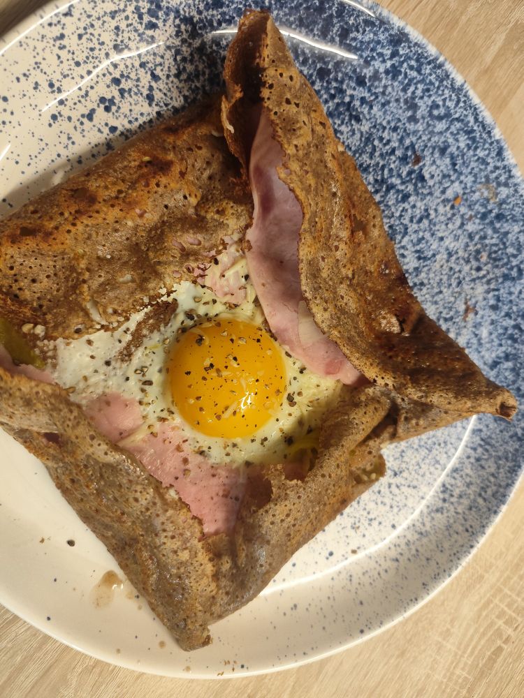 Une galette complète oeuf, jambon, fromage sur une assiette.