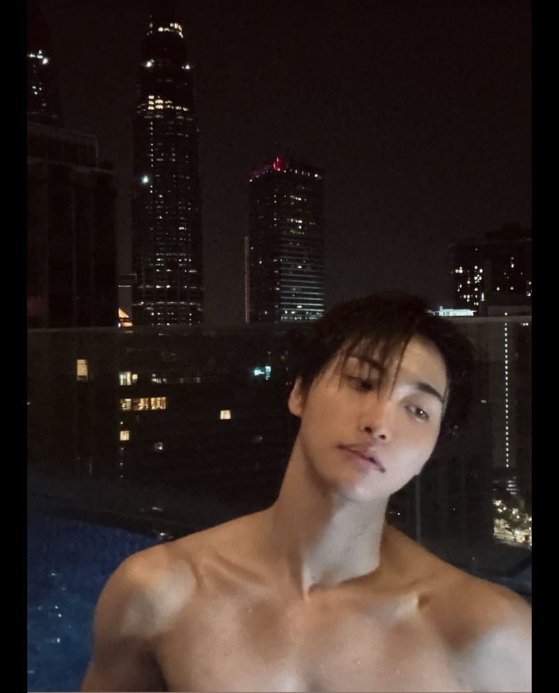 Seonghwa’s Instagram photo of himself barefaced in a rooftop pool in Kuala Lumpur, at night. He’s shirtless, clavicles on full slutty display, and he’s looking coolly off to the right like a model.