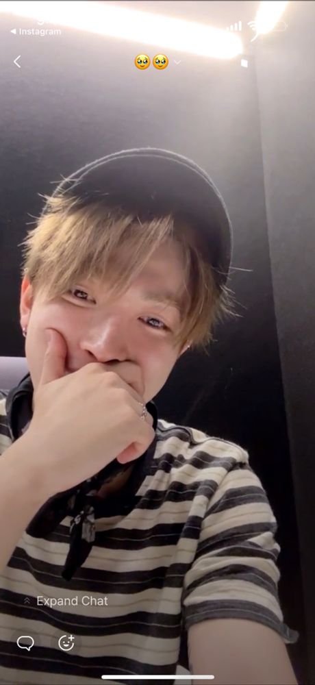 Closer up shot of Hongjoong on pop live, holding his hand up to his mouth and smiling down at the camera