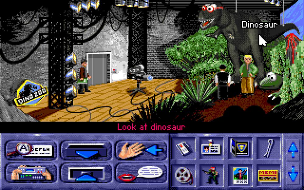 A scene from "Bi-Fi: Action in Hollywood". Lukas is on the set of a movie featuring dinosaurs. He stands in front of a T-Rex three times his height. The T-Rex is wearing red glasses. A sign by the doo is similar to the design of the Jurassic Park logo, and reads "Dino Zoo".