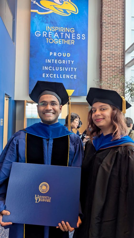 2 people in their doctoral regalia smiling at the camera. 