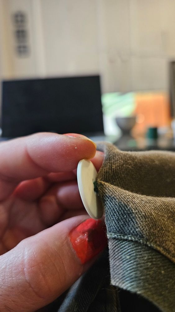 behind a white button on camo patterned pants you can see the thread wrapped around the base of the four threads holding on the button. The wrap helps keep the button tight while also maintaining a small distance between the pocket and pocket flap when closed. 