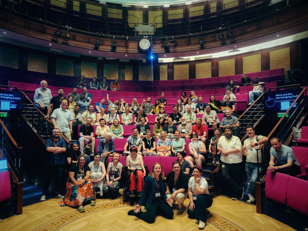 A large group of people posing in front of lecture theatre seats