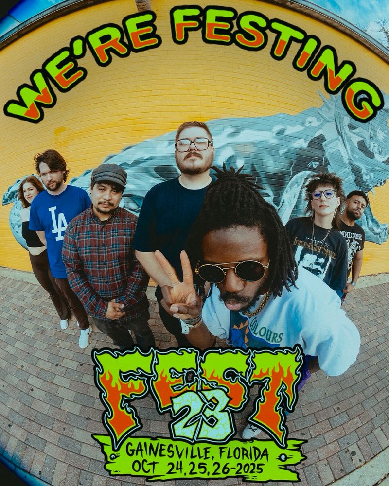 A picture of the JER band standing in front of a yellow walll with a chrome gator painted on it. from left to right is candice, Ricky, Esteban, woody, JER, Emily, and Javi. JER is closest to the camera throwing a peace sign 

Text in front of it reads “we’re festing” up top and “fest 23, Gainesville Florida, October 24th, 25th, 26th 2025” 