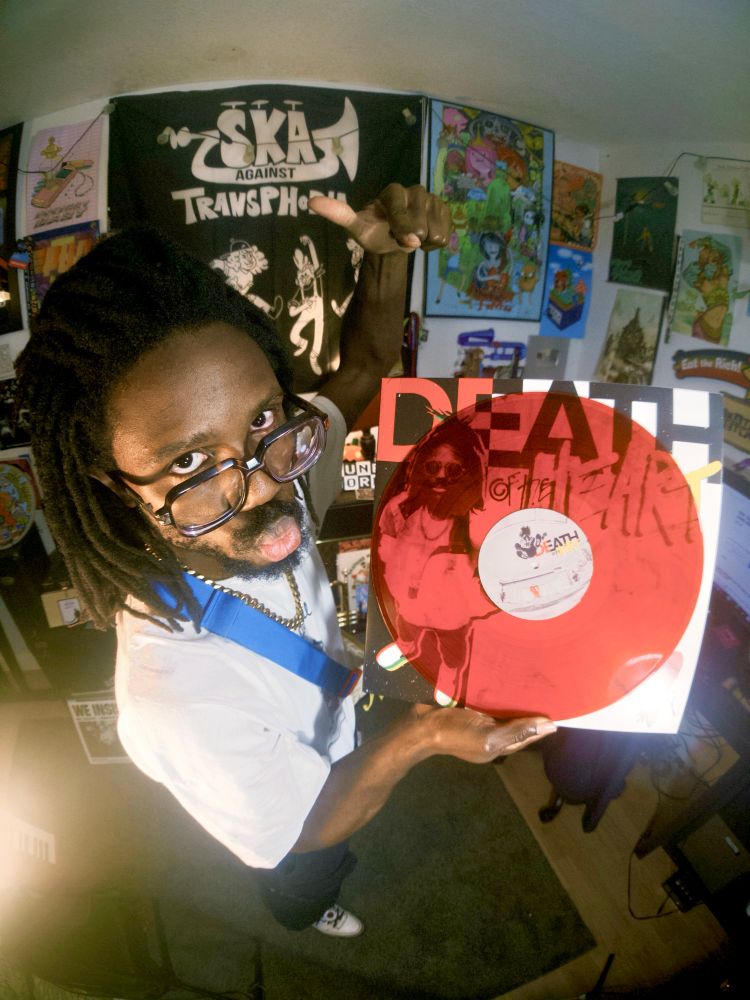 JER holding a copy of the smoke red vinyl variant of death of the heart. The vinyl appears to be transparent, and you can see the album art behind it 