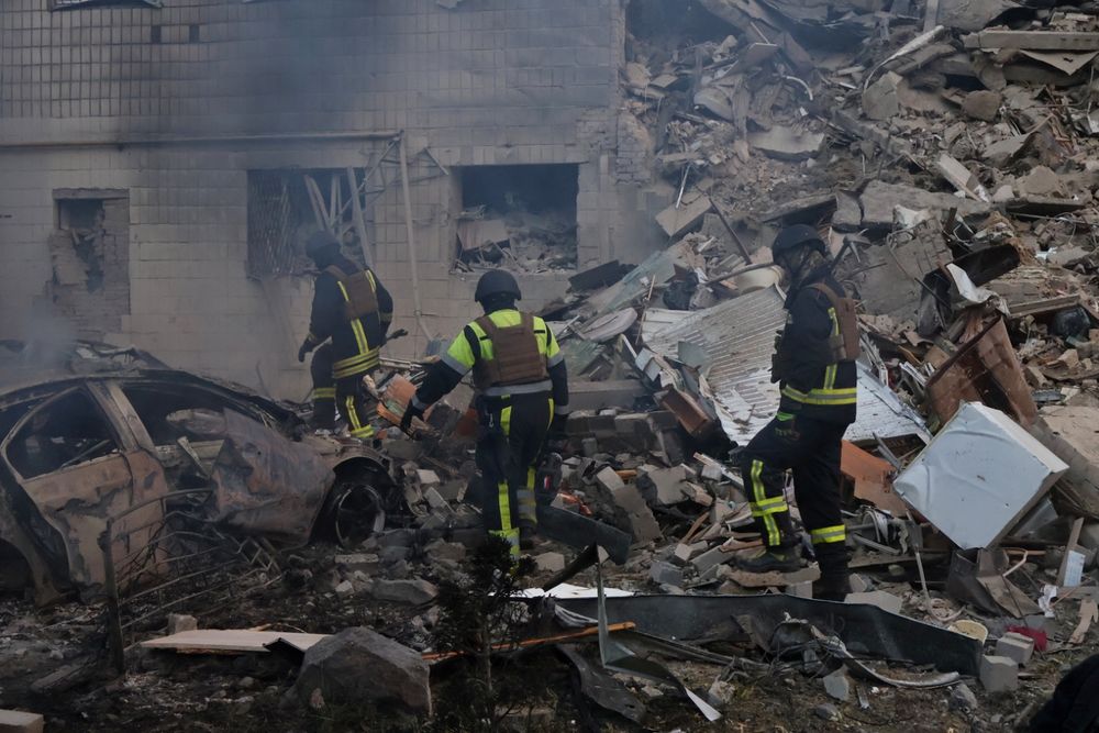 eine Gruppe von Feuerwehrleuten vor einem zerstörten Gebäude in Kyjiw.

(c) picture alliance / ZUMAPRESS.com | Aleksandr Gusev