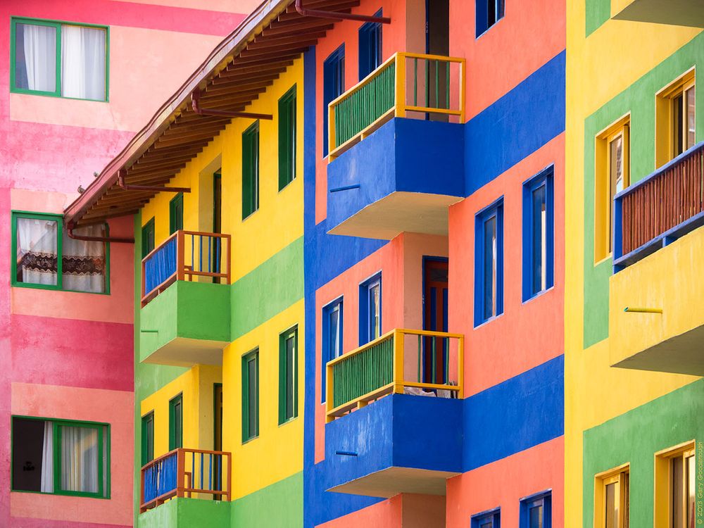 Apartment walls in the area of Guatapé, Antioquia, Colombia, South America. The walls, window trim and balconies are painted multiple colors including, blue, green, yellow, red and orange.