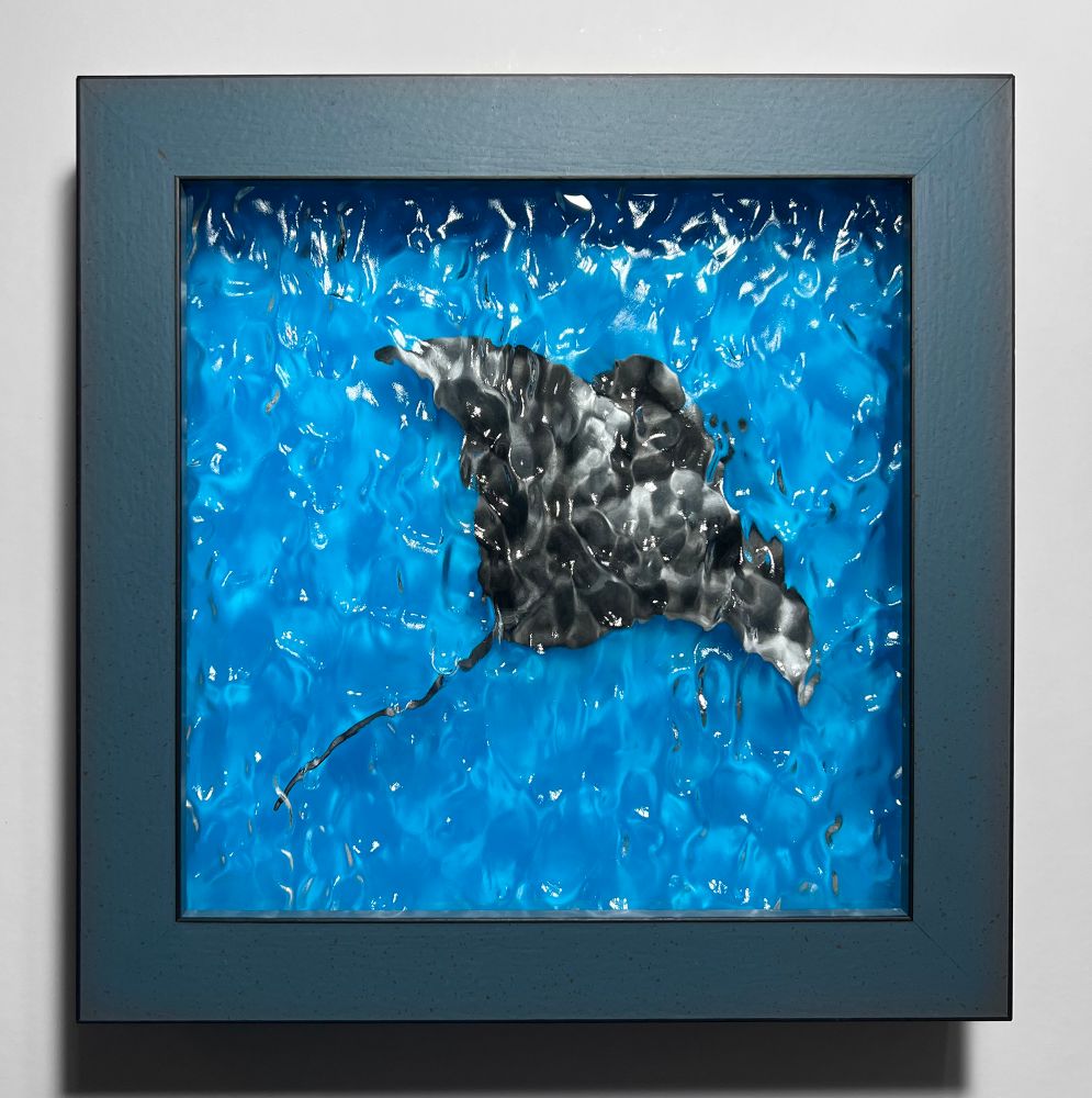 Framed manta ray artwork with a glow in the dark acrylic background and a water textured acrylic top layer. This is how the piece looks in daylight. 