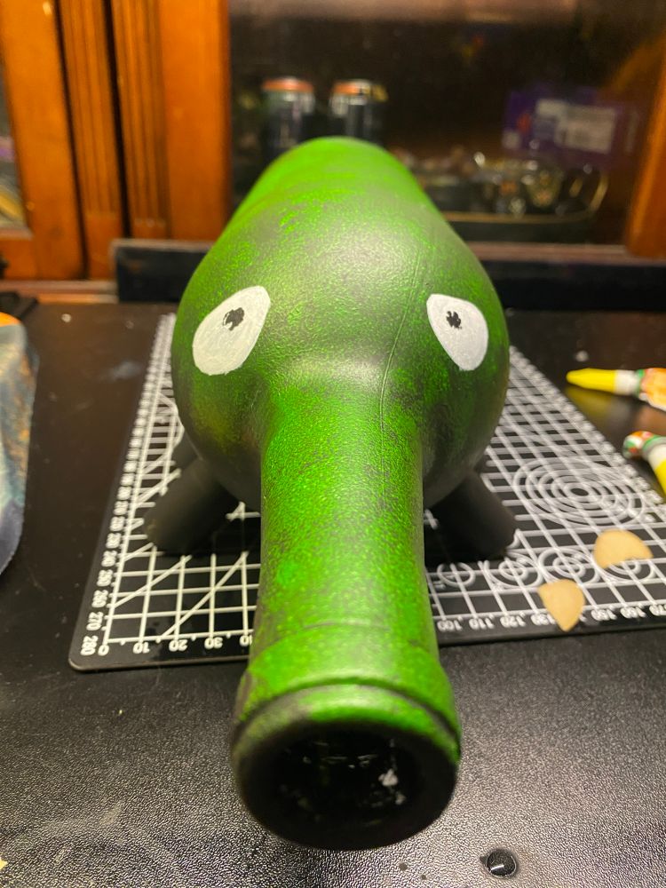 A monster made out of a wine bottle laid on its side and now has 8 feet made of corks! He was painted black and has a mossy top like appearance. Crooked eyes & crooked pupils 