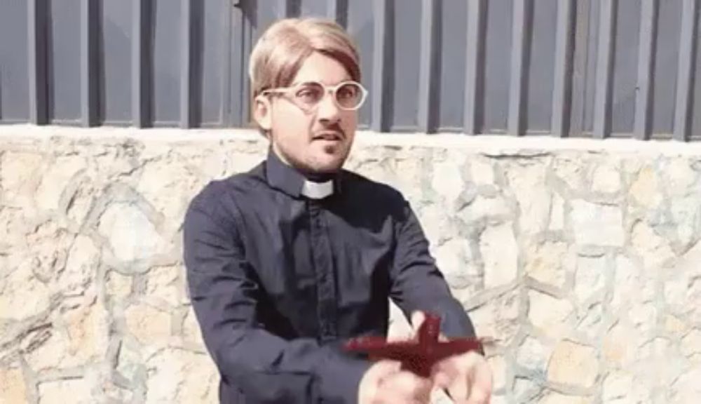 a man in a priest 's robe is holding a red cross in his hands .