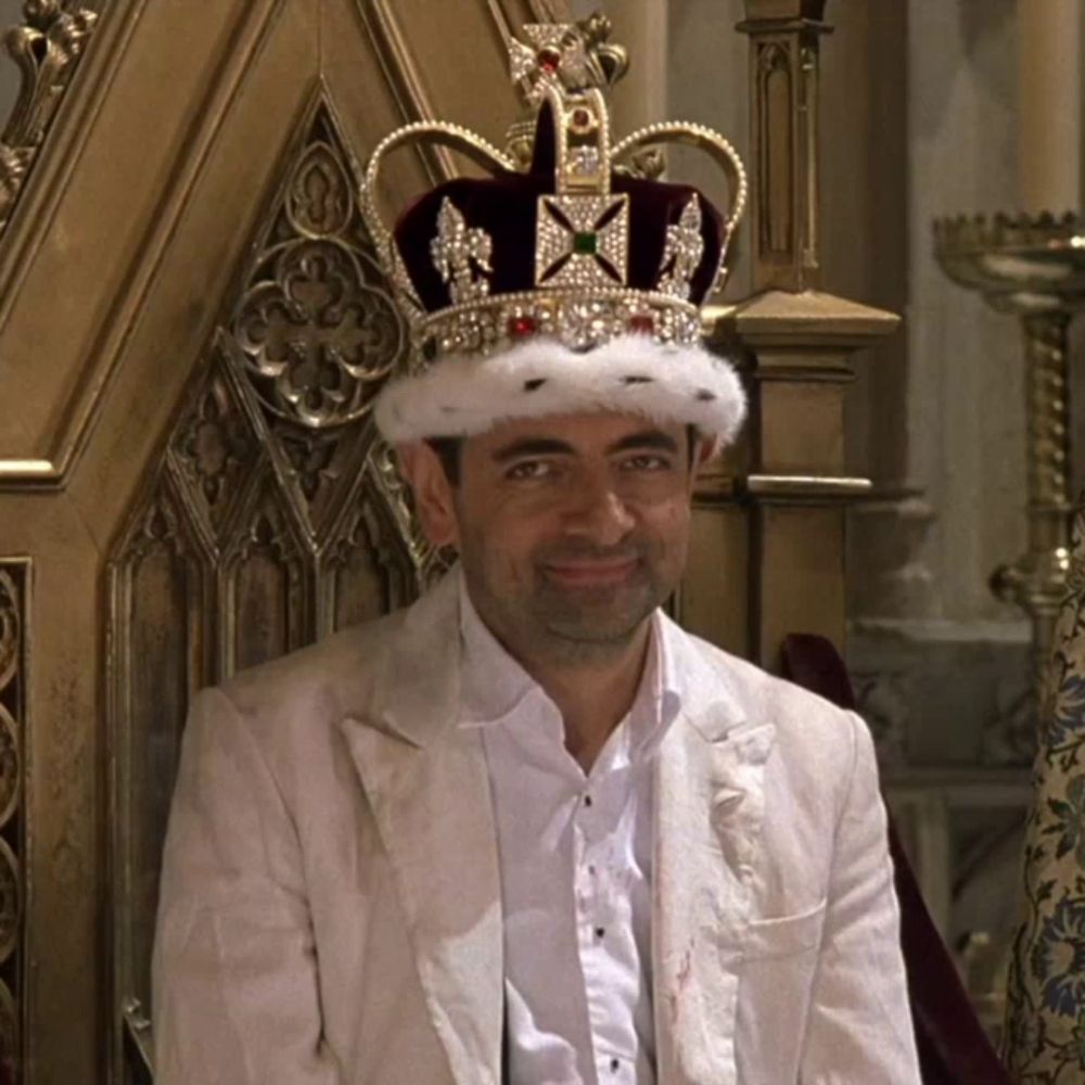 a man wearing a crown is sitting in a chair