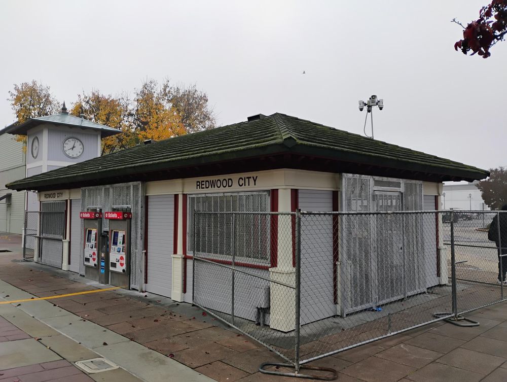 This is the waiting shelter at Redwood City.  It's basically a roof with some pillars holding it up, and some partial walls, but basically open air.  Now a bunch of metal grates have been put up so nobody can get in there.  Ticket machines have been moved out of the structure so they face the outside through precisely-sized gaps in the grates.
