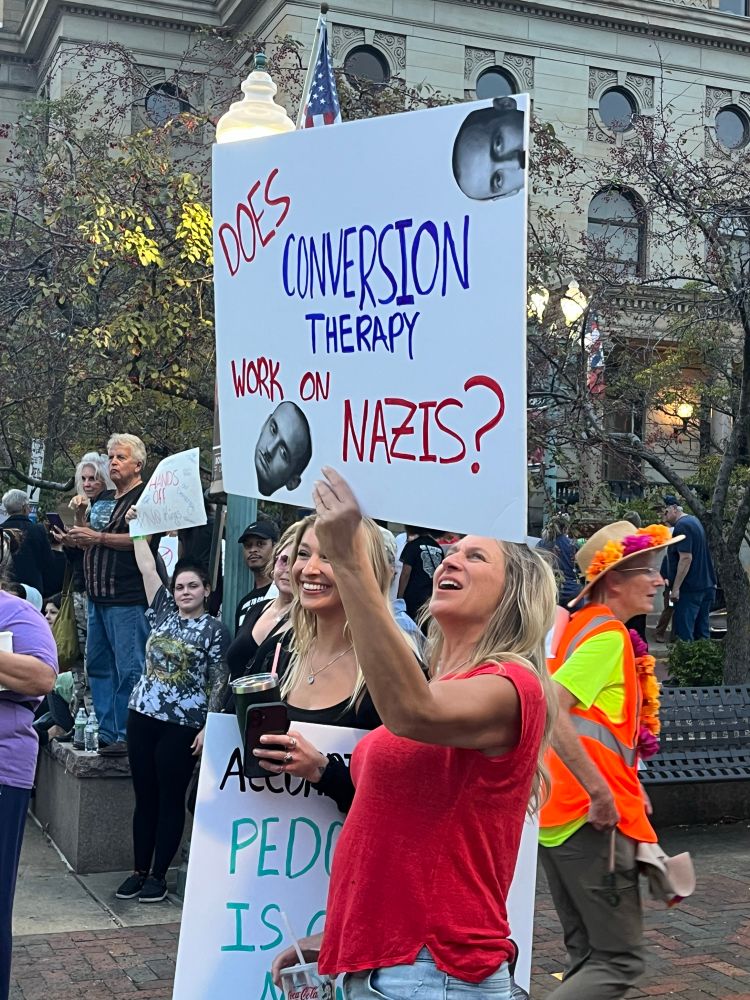 Sign reads “Does conversion therapy work on Nazis?” with a cutout of Stephen Miller.