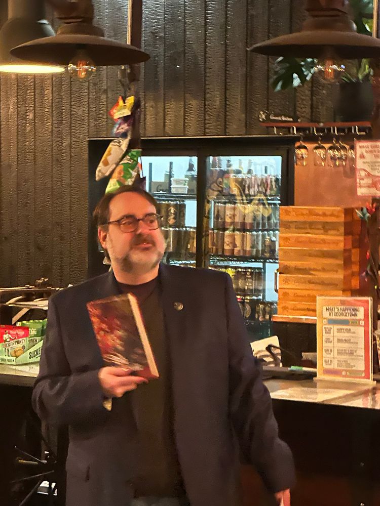 Andrew Romine waves his new book The Mosquito Fleet in front of the bar 