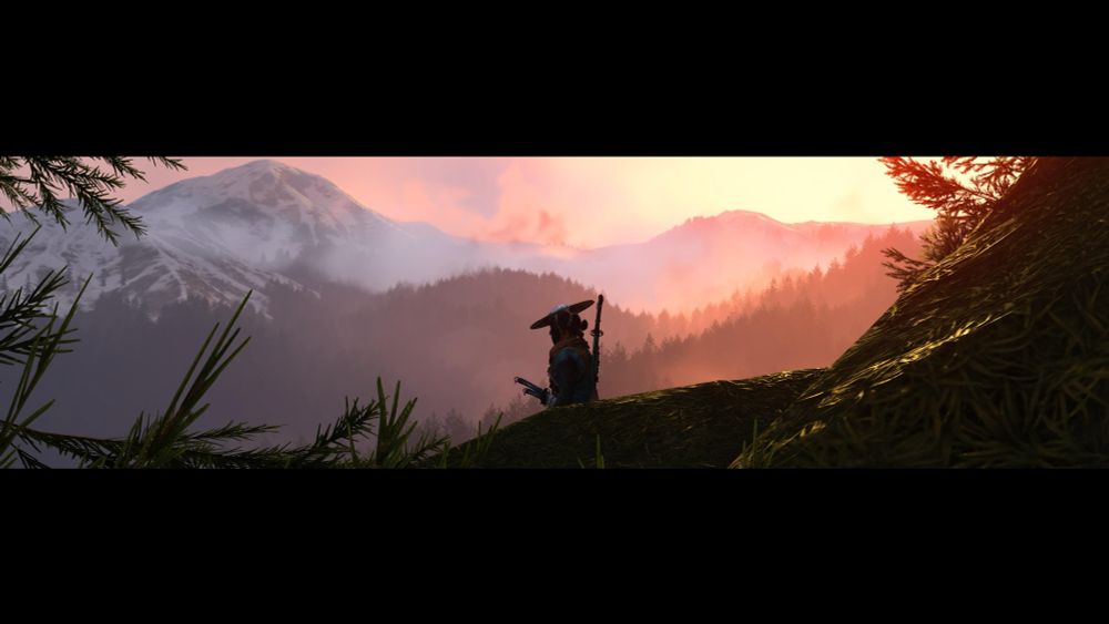 Atsu framed against a sunset, snow-capped mountains in the background, forested hills in the foreground.