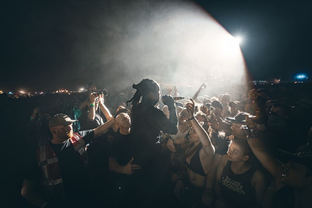 The Prodigy-Sänger Keith Palmer alias Maxim Reality steht beim Hurricane Festival vor der Menschenmasse im Scheinwerferlicht. 