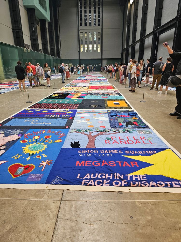 A low shot of a long display of memorial textile art in bright colours.