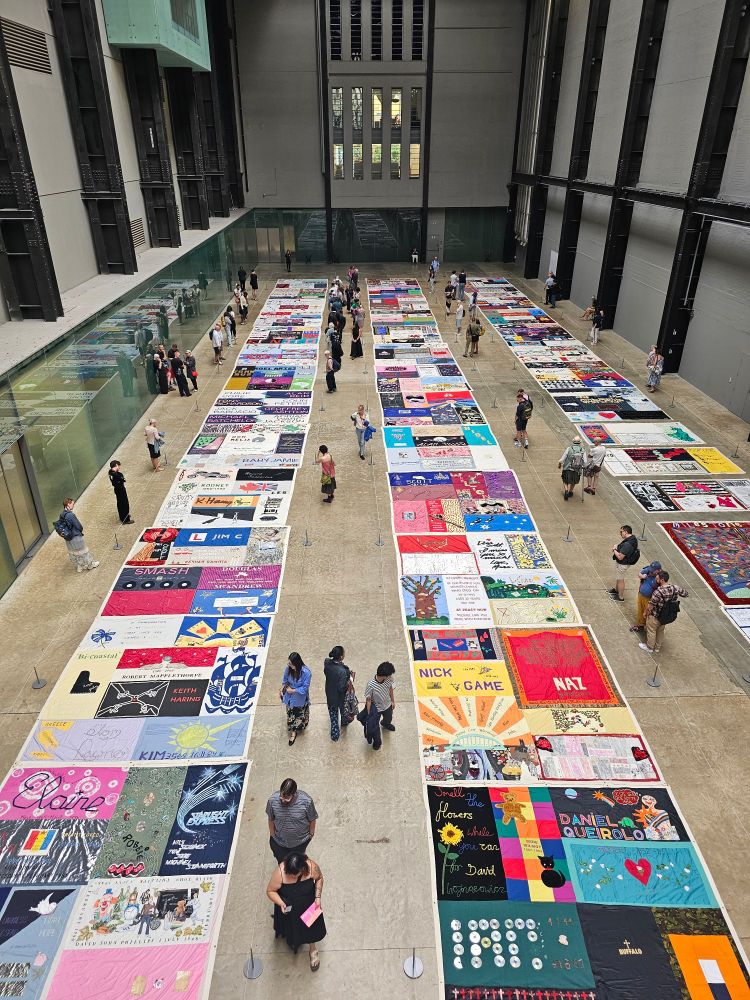 A top-down view of a display of hand-painted and sewn textile art in bright colours.