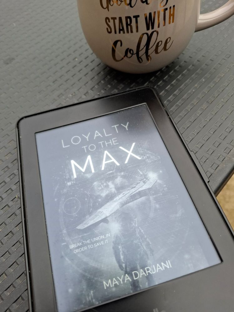 Kindle with the cover of Loyalty to the Max,  with a space ship and astronaut.  The tag line is Break the Union in order to save it. Also pictured is a mug of coffee