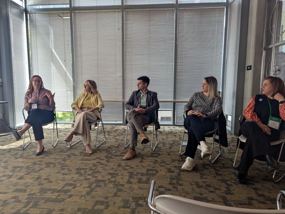A panel of six people gives a presentation to an audience