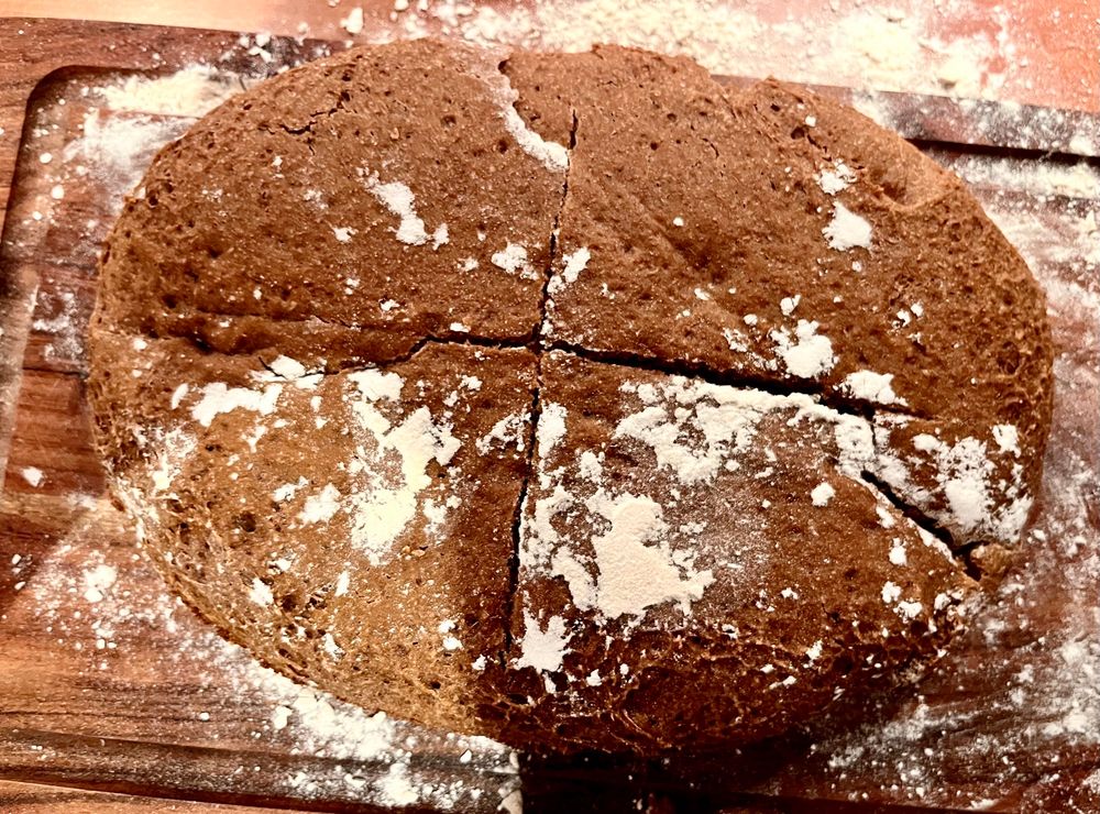 A large brown whole grain loaf with  strains of white flour on it
