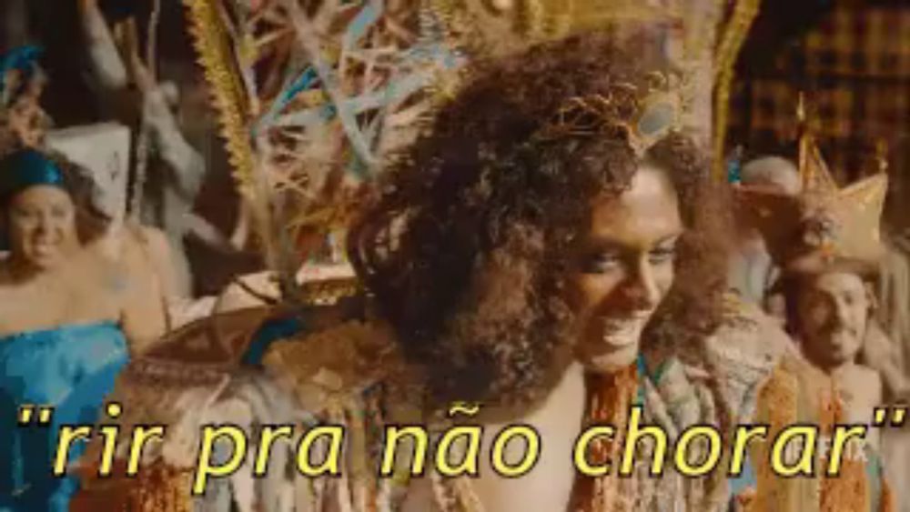 a woman in a carnival costume is smiling with the words rir pra nao chorar behind her