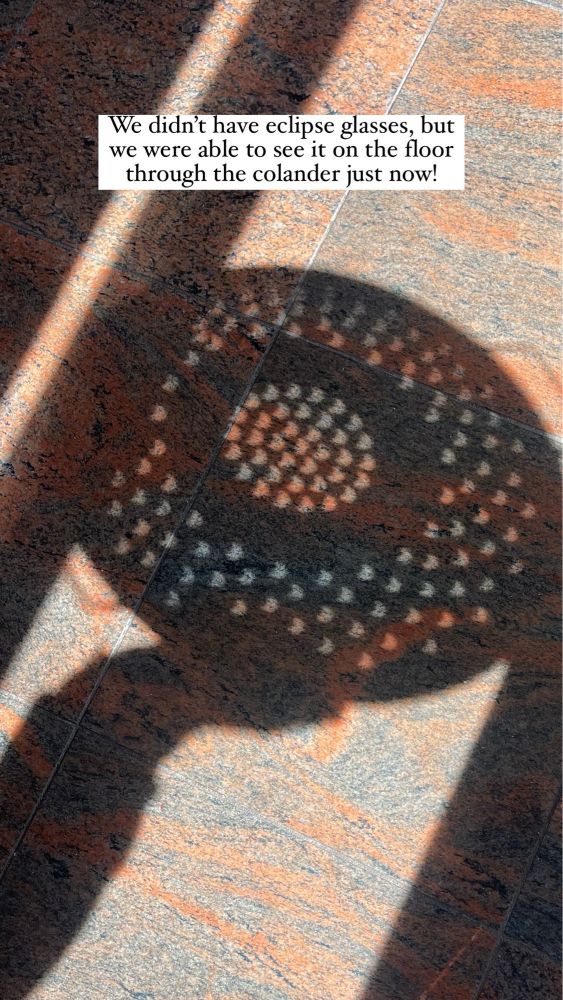 Colander shadow showing partial eclipse in San Francisco on kitchen floor. Superimposed text: We didn’t have eclipse glasses, but we were able to see it on the floor through the colander just now!