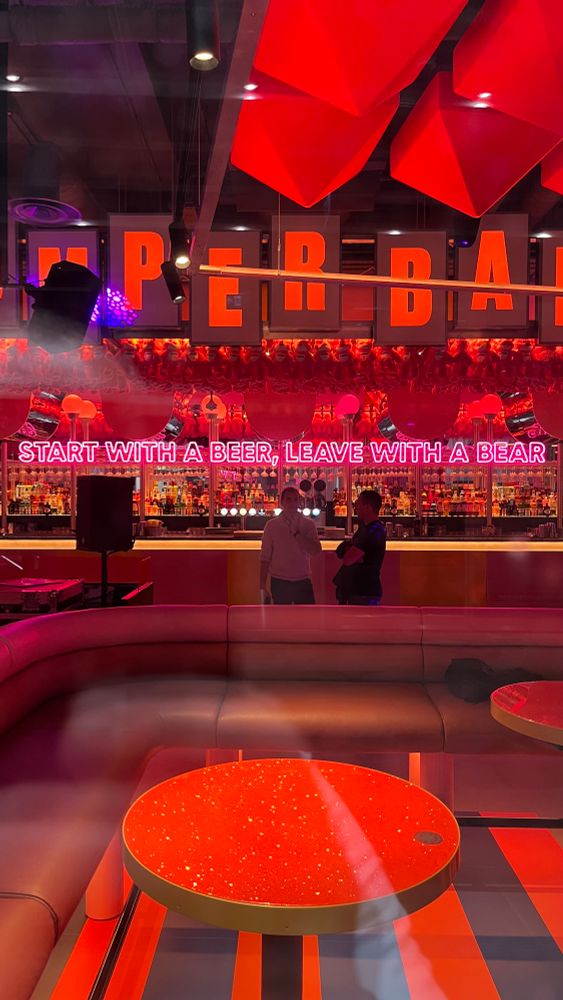 Red-lit bar with neon slogan Start with a beer, leave with a bear