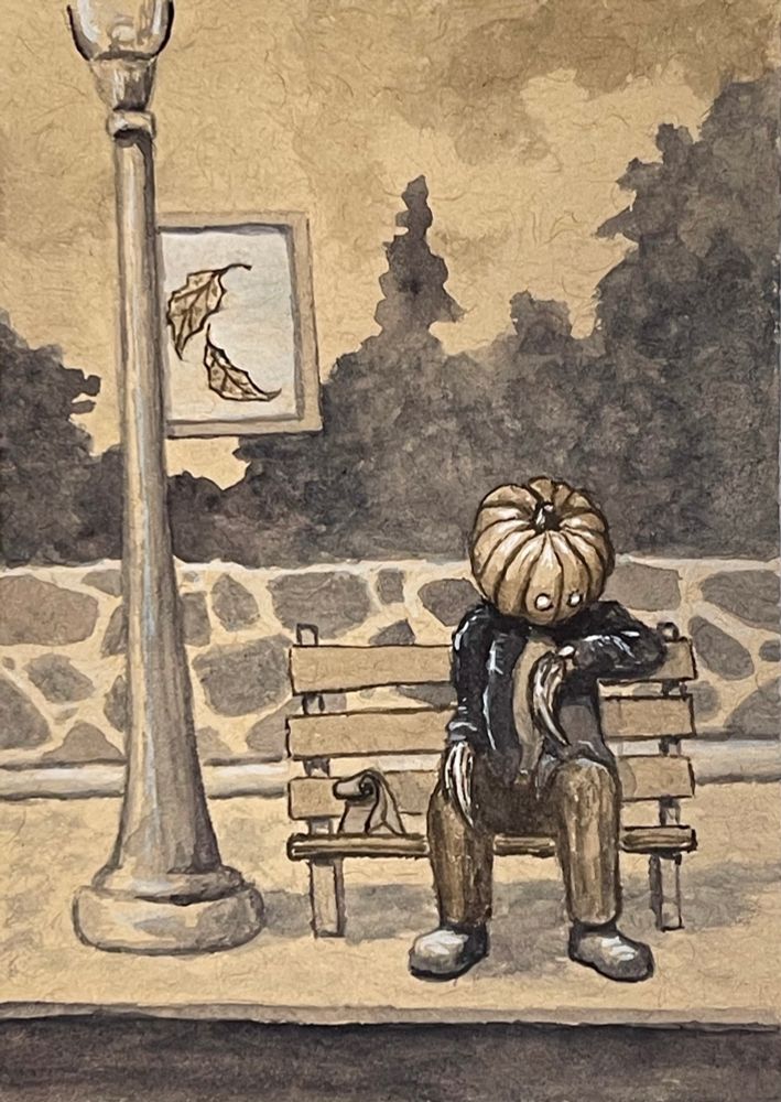 A pumpkin-headed fella with shocks of hay for hands looks at his watch as he sits on a bench at a bus stop. A sign on a pole depicts leaves falling. There is a paper lunch bag on the bench. 