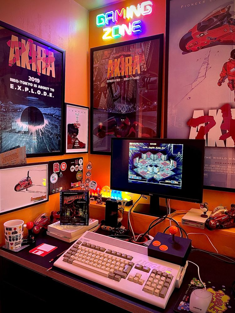 An Amiga A1200 on a desk, surrounded by Akira posters. The game Roguecraft can be seen on the monitor.