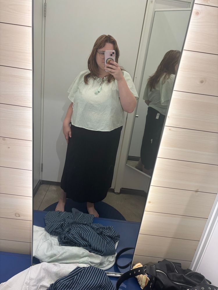a picture of me in a different dressing room. i’m wearing a pastel green top with thin white stripe. my bottoms are a long, basic black skirt