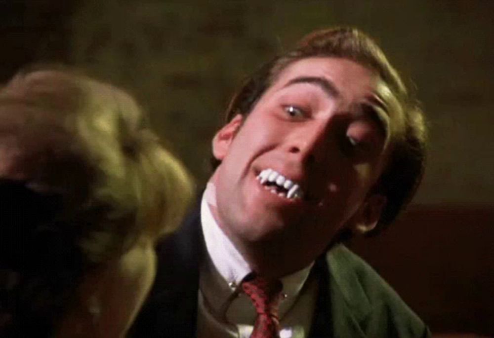 a man in a suit and tie with vampire teeth on his face