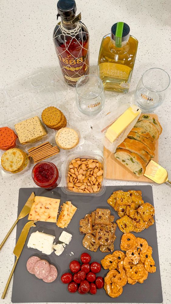 Charcuterie board with crackers, cheeses, nuts, bread, jelly, and cherries