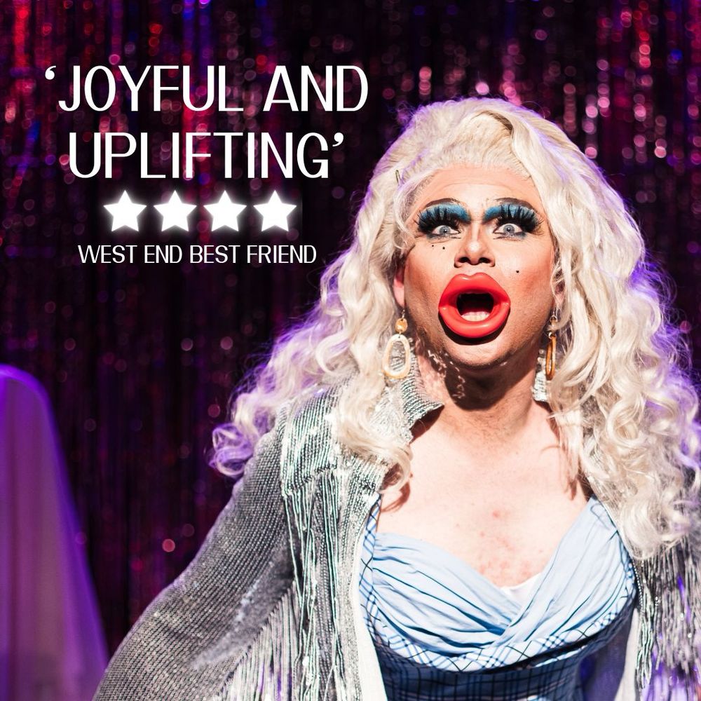 ‘Joyful and Uplifting’ 4 star review West End Best Friend for Drag Baby. A blonde drag queen with comically large prop red lips in the middle of a lip sync routine. 