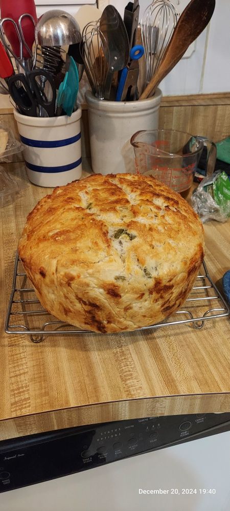 Loaf of sourdough bread fresh out of the oven, sitting on a cooling rack.