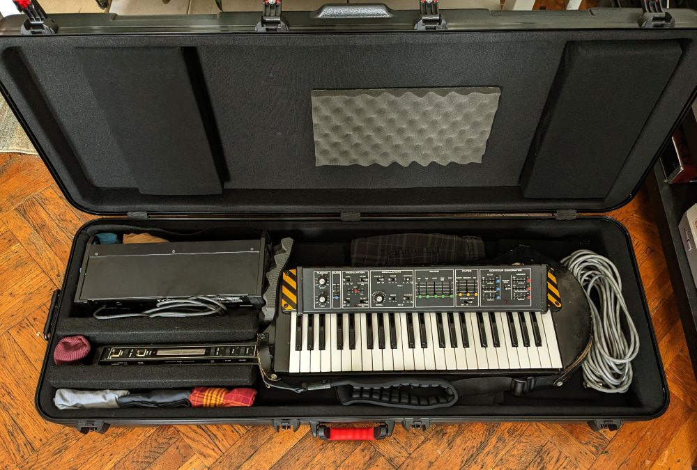 Photo of my Moog Liberation synthesizer in a flight case, with improvised arrangement of internal padding that includes velcro panels and partitions as well as my own clothing, socks, and underwear 💪