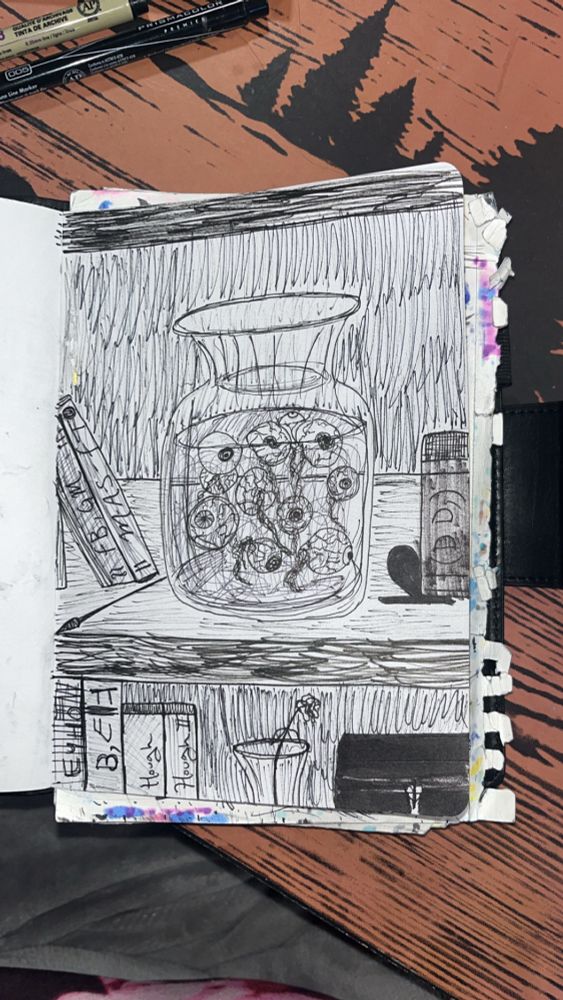 A black and white drawing of a large, clear vase full of eyeballs placed on a wooden shelf. The eyeballs are facing in multiple directions and are floating in liquid. They vary in size and darkness of irises, pupils, and veins. There are books on both sides of it, as well as underneath on the other shelf. Another case in also on that shelf, but smaller and with a wilted flower in it. Next to that is a black lockbox. There is a lot of linework. 
