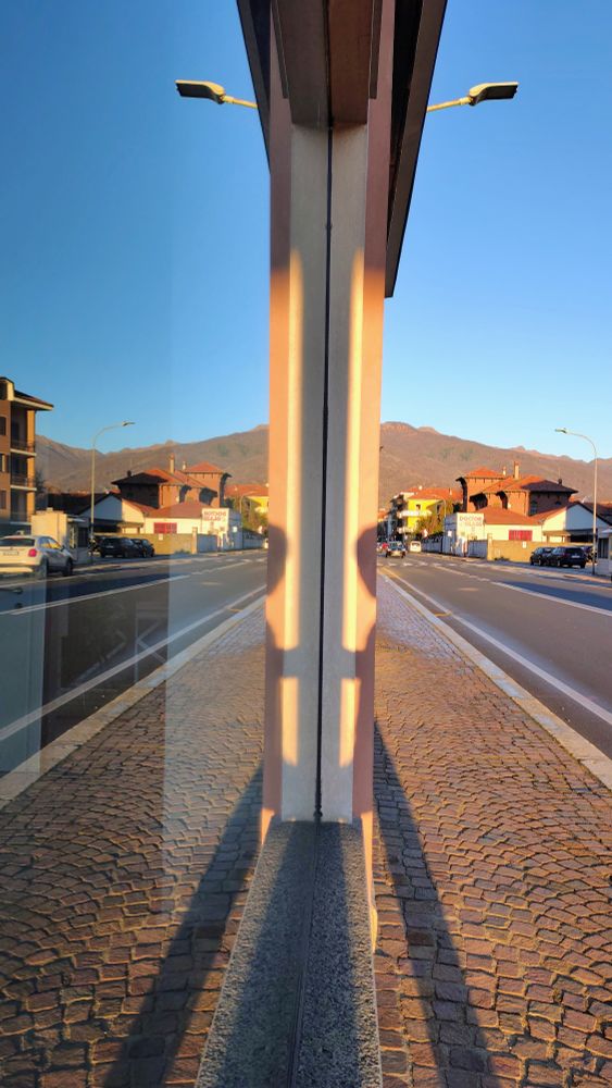 Una strada di una cittadina riflessa nella vetrata di un negozio in una giornata di sole.