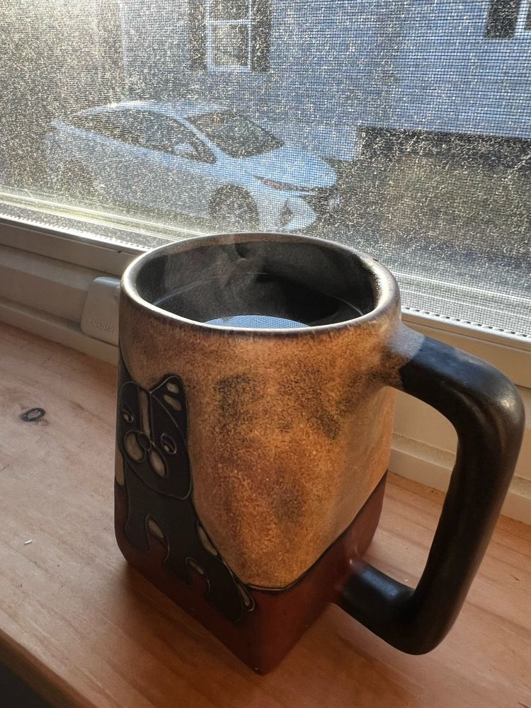 An image of a steamy cup of coffee on a windowsill 