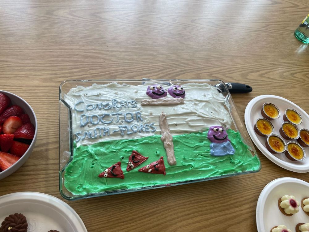 A glorious cake, made by Bill Pepe, featuring Blender-style social characters and the message "Congrats Doctor Smith-Flores"