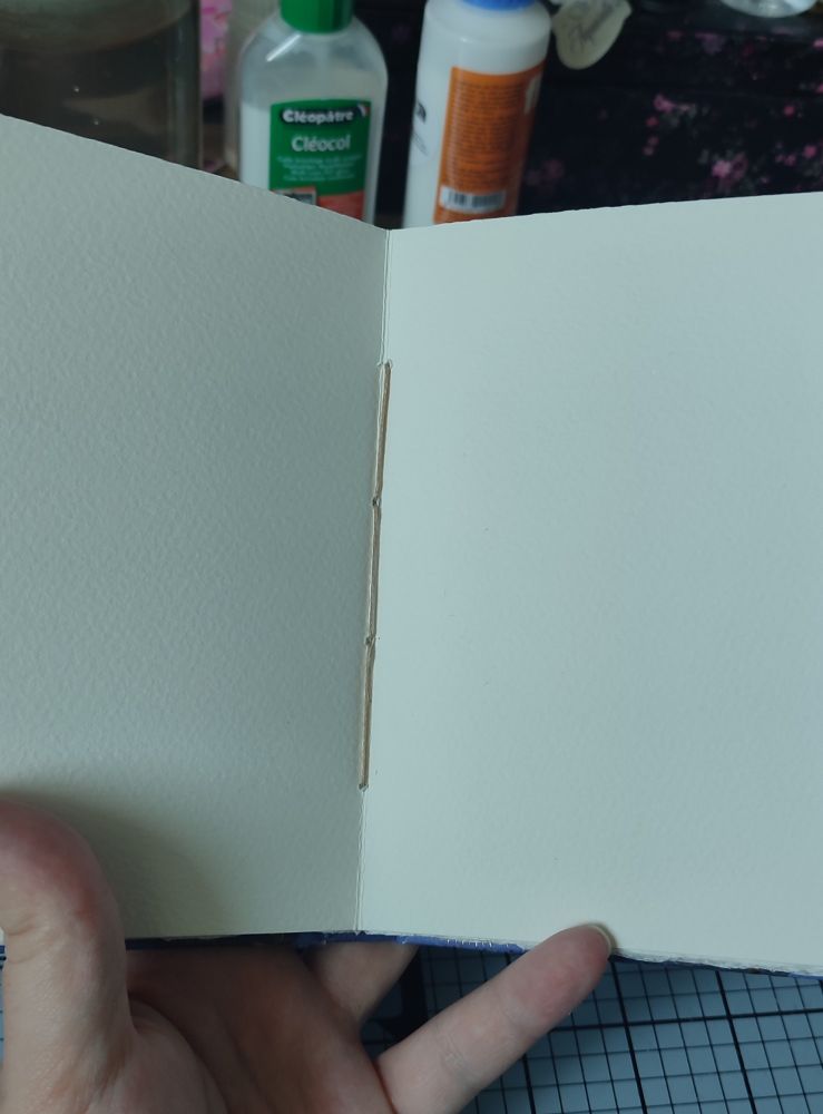 Photo du centre d'un feuillet montrant une reliure bien régulière avec un fil ciré beige. 
