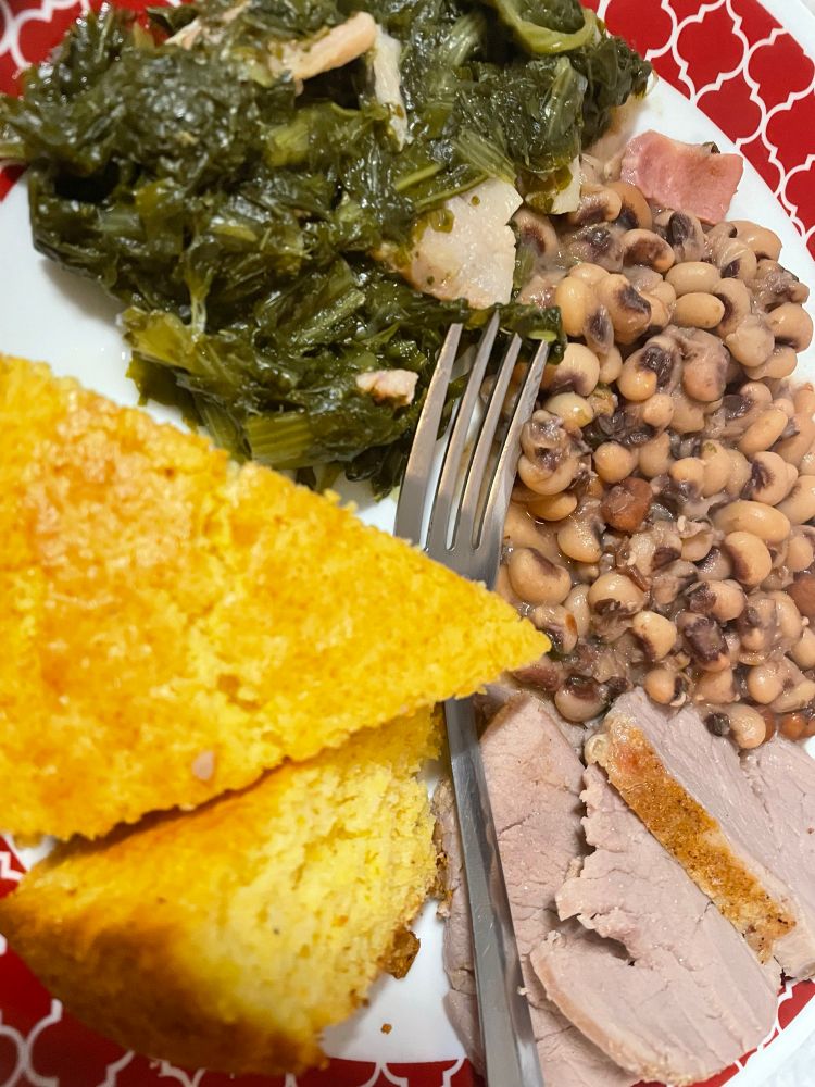 Plate with collards, black eye pease, pork loin.  And cornbread 