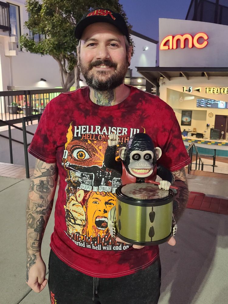 Me holding an AMC popcorn bucket modeled after NEON's The Monkey