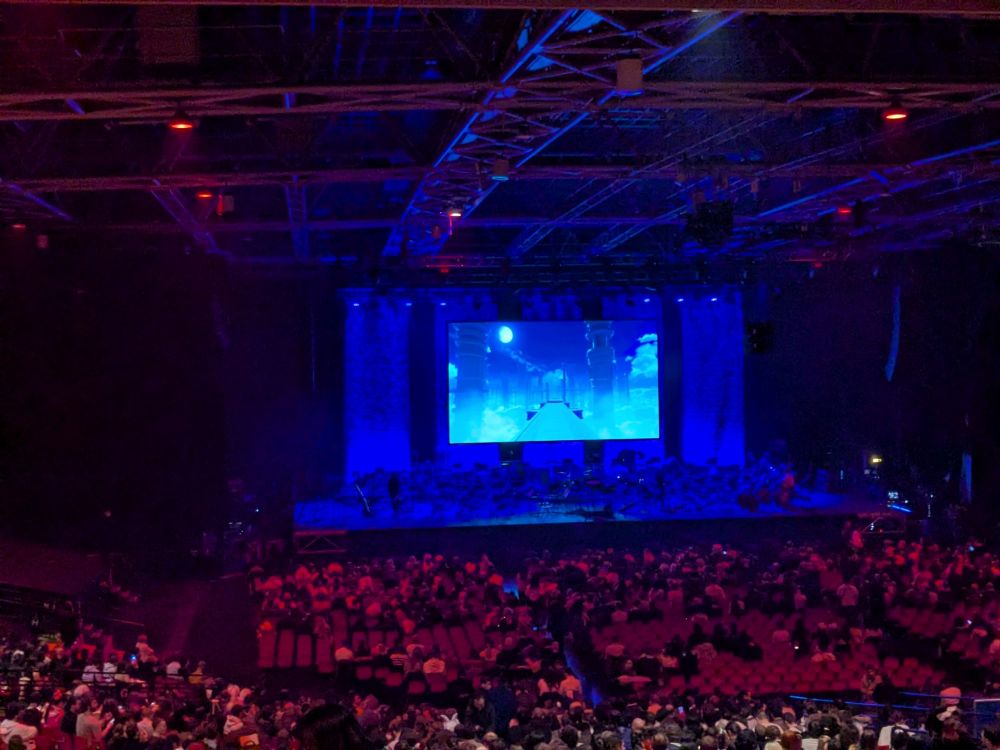 Concert hall with the genshin loading menu on a screen.