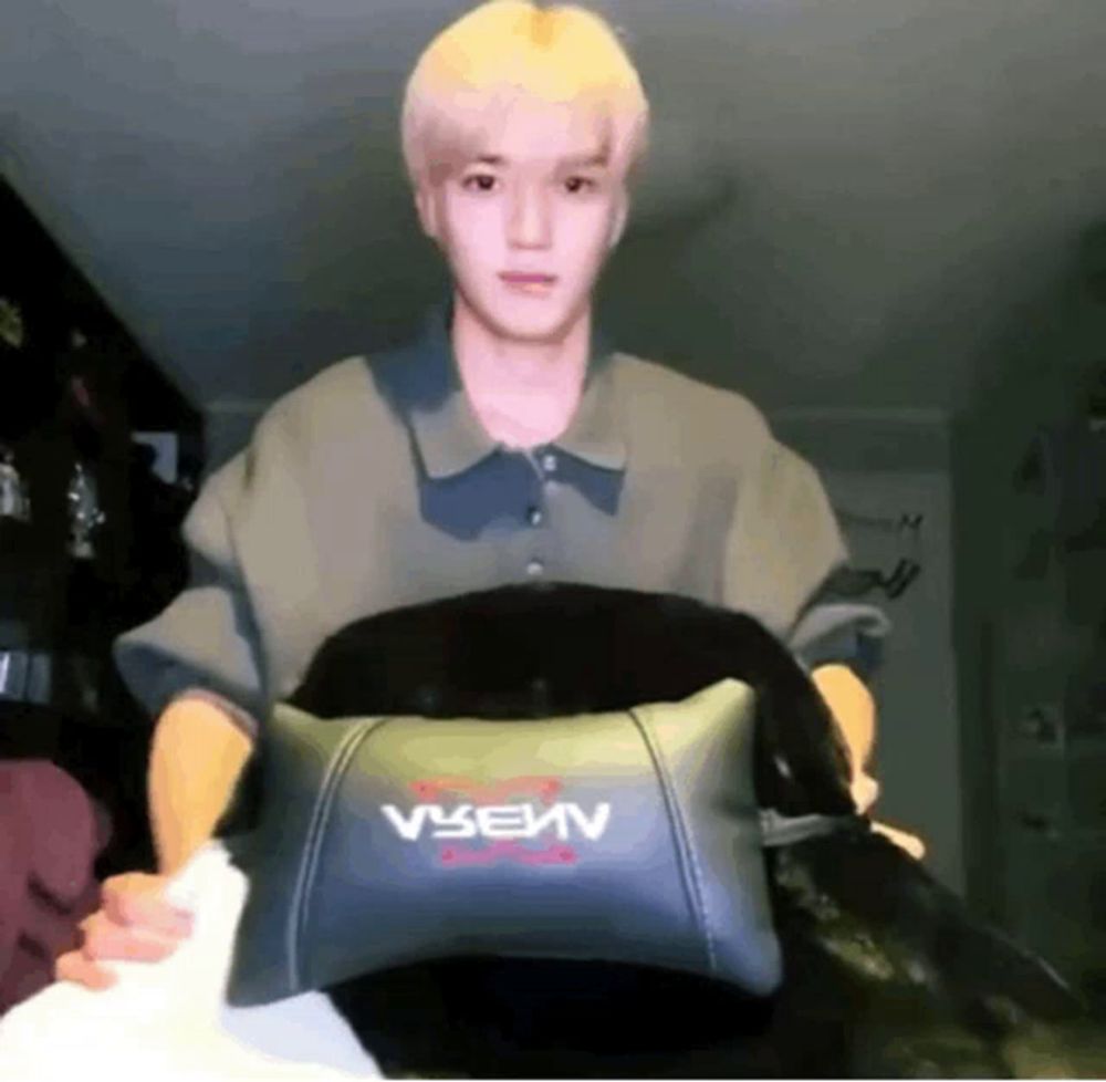 a man is holding a pillow with the letter v on it in his hands