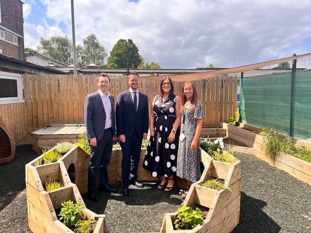 Two men and two women stand surrounded by wooden planters