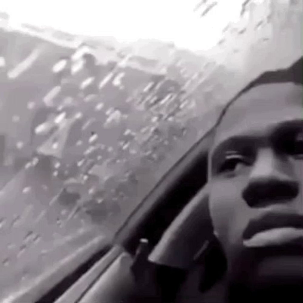 a man is smoking a cigarette while driving a car in the rain .