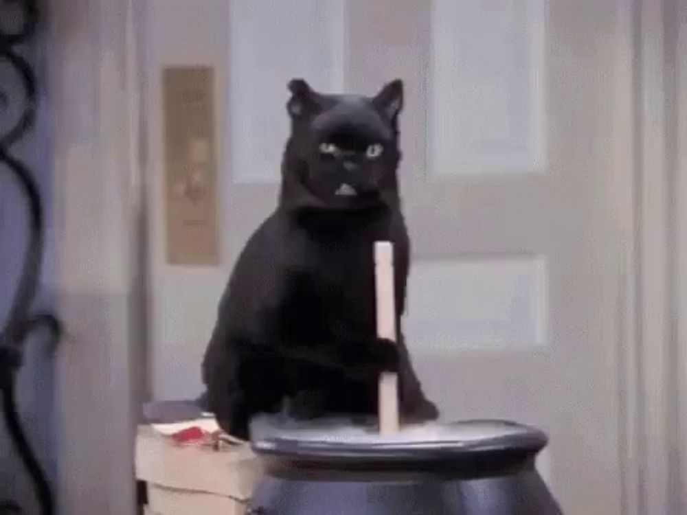 a black cat is sitting on top of a cauldron holding a stick in its mouth .