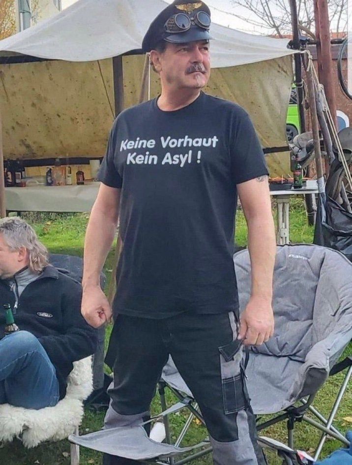 Ein Faschospinner trägt ein Shirt mit der Aufschrift "Keine Vorhaut, kein Asyl."