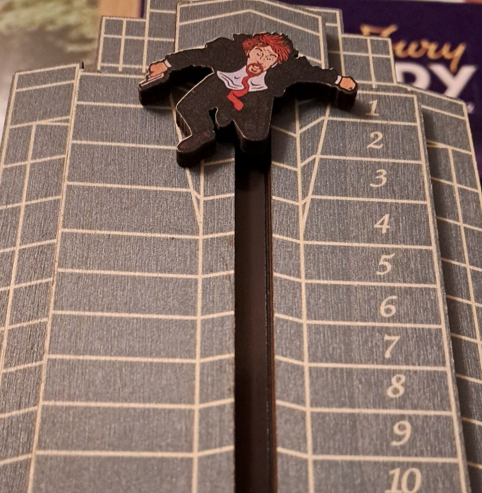 Wooden advent calendar: fictional terrorist Hans Gruber off of Die Hard falls from the Nakatomi Tower, his left hand indicating today's date.